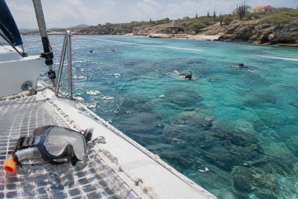A catamaran anchored in clear turquoise water near a coral reef