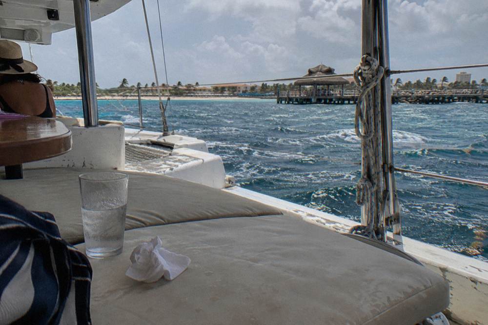 A shaded seating area on a catamaran deck with cushions and a clear view of the open sea