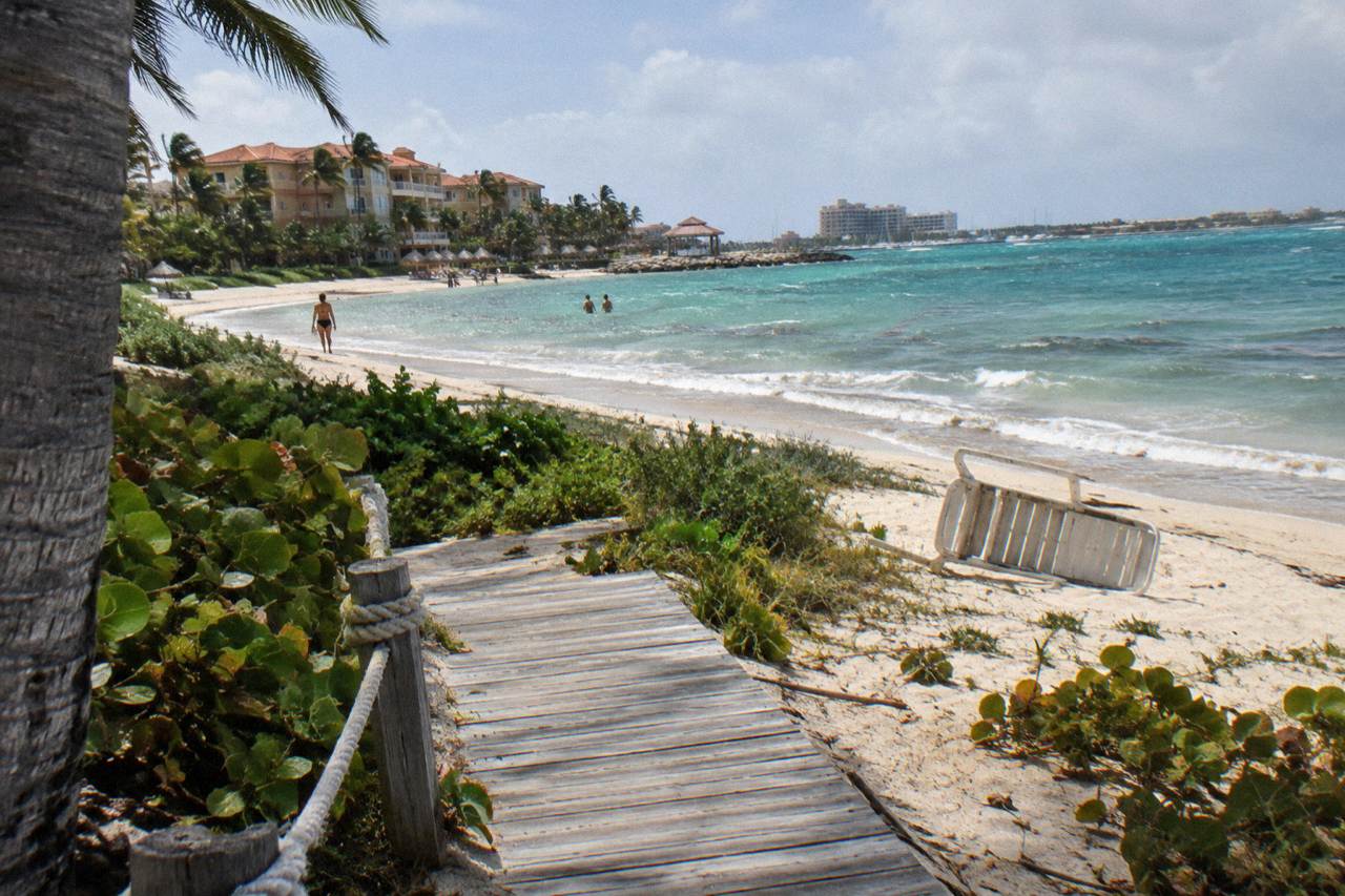 A private island beach with calm turquoise water and a wooden walkway