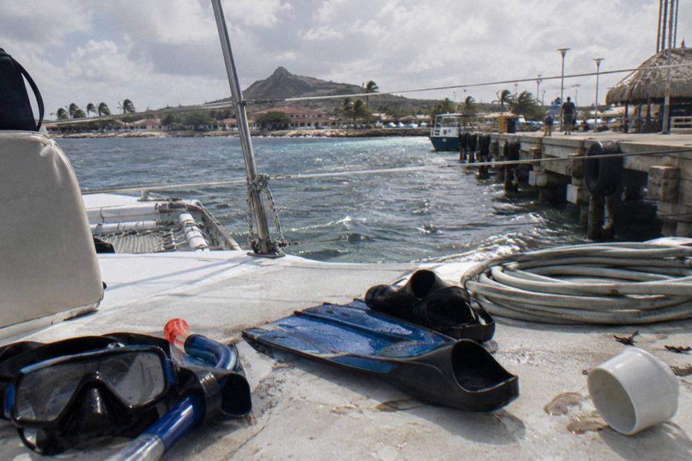 A catamaran deck with snorkel gear laid out and calm sea beyond the railing