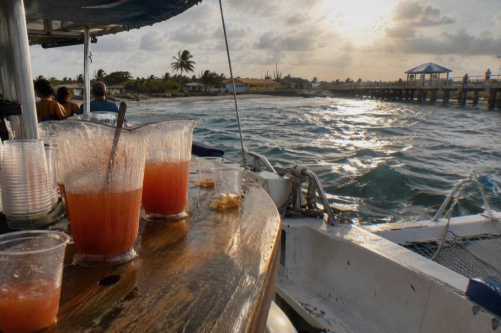 A deck bar with cold drinks and glasses arranged on a wooden counter at sea