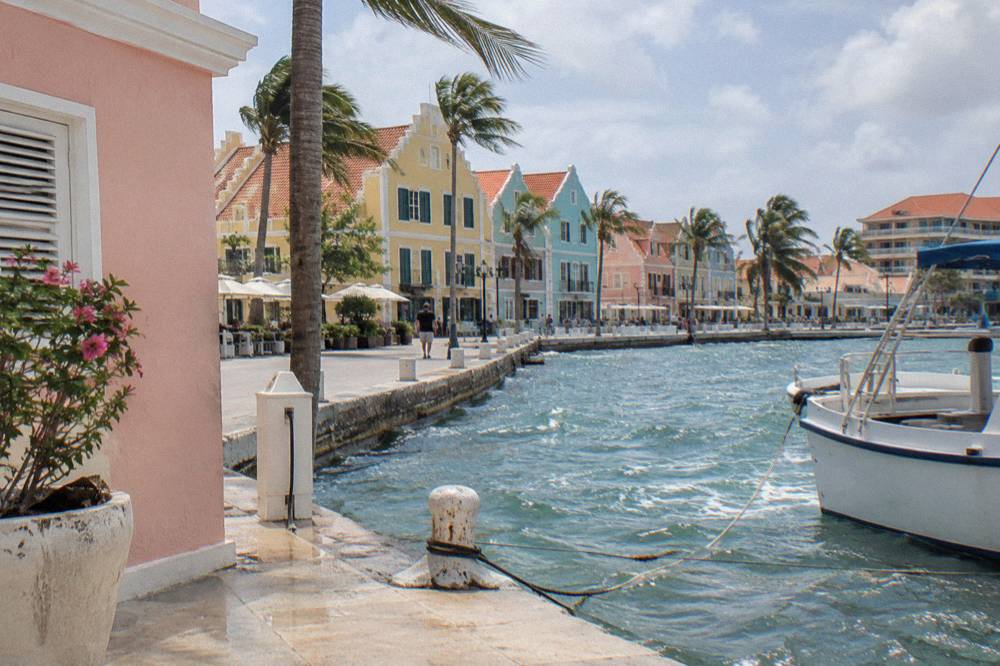 Colorful Dutch colonial storefronts along a clean street in central Oranjestad under a bright sky