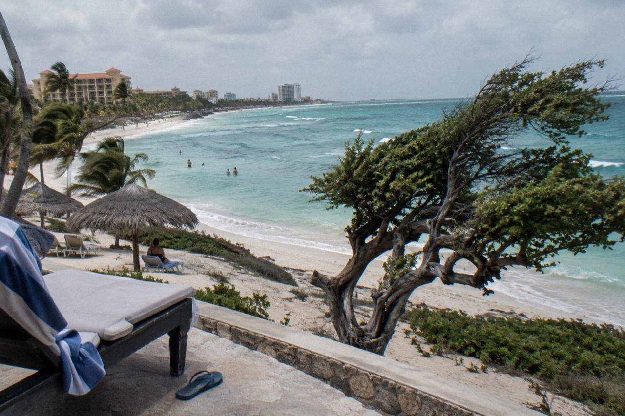 White sand beach in Aruba with calm turquoise water and a row of beachfront resort towers along the shore