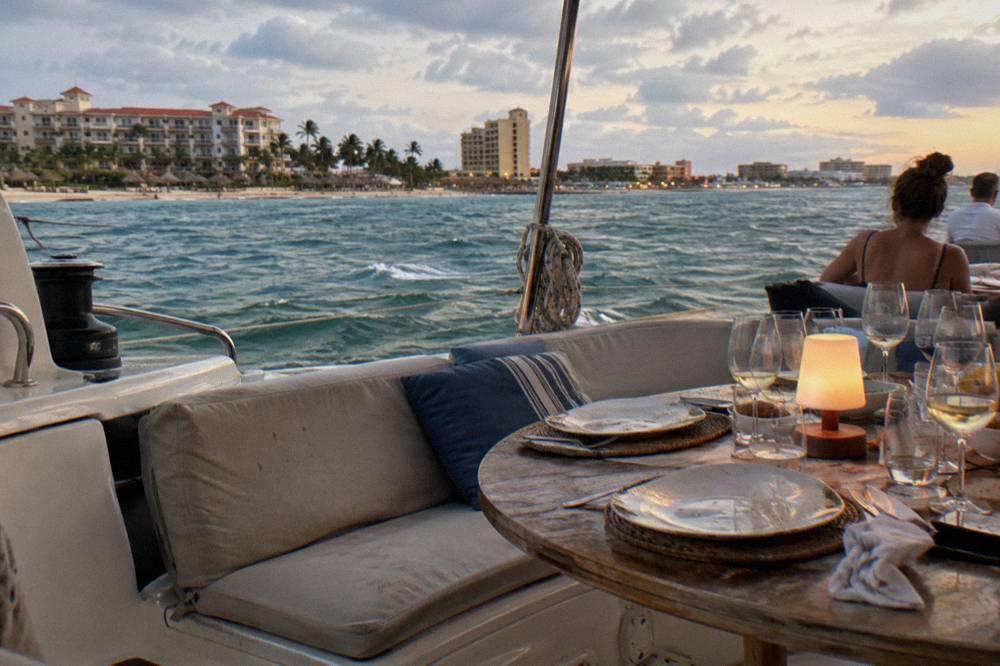 Dinner table set on a catamaran deck with glasses and plates at dusk