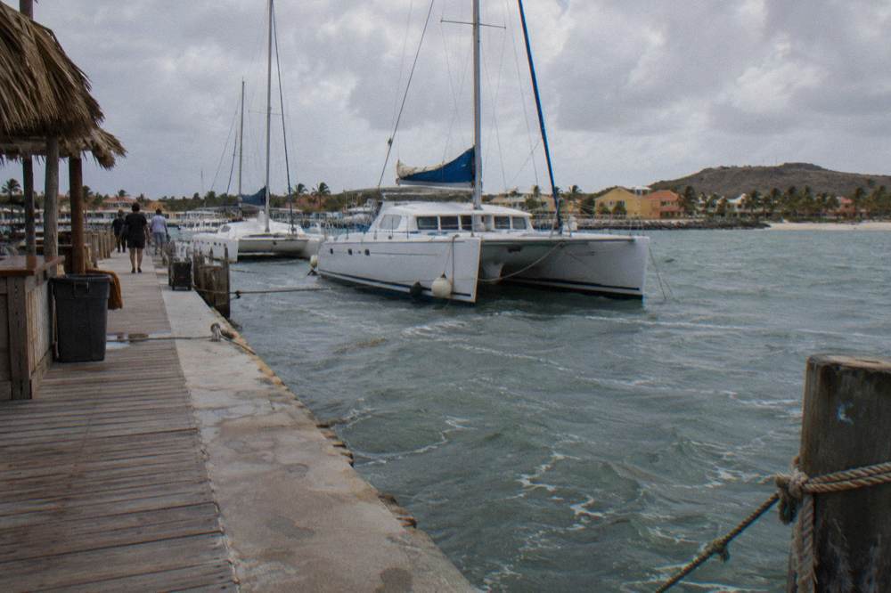 Wooden pier extending into calm Caribbean water with catamarans moored nearby