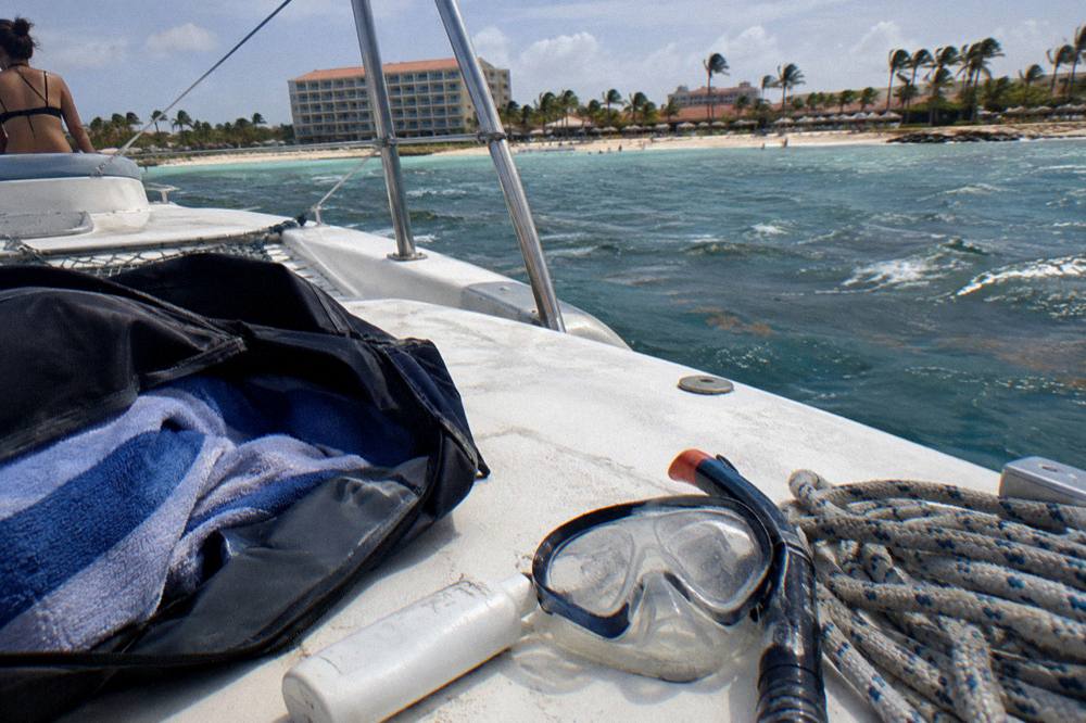 A bag with towel, sunscreen bottle and snorkel mask arranged on a boat deck