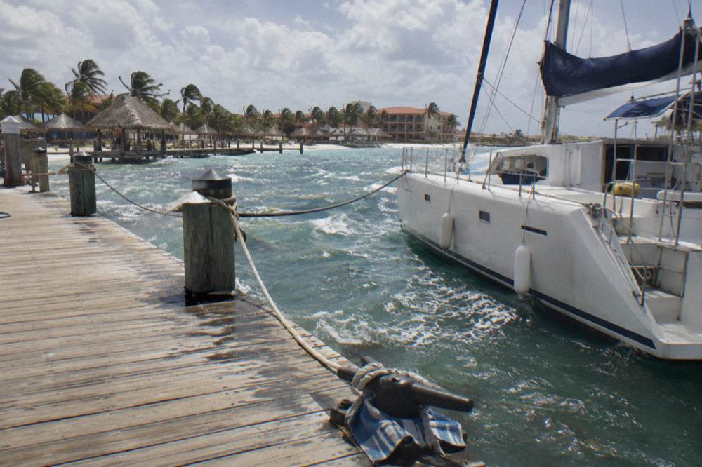 Wooden pier extending into calm blue water with catamarans moored nearby