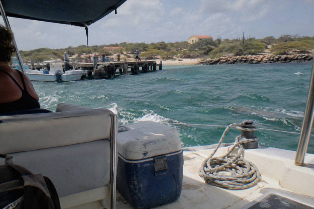 Wide catamaran deck with shaded seating area over calm turquoise water