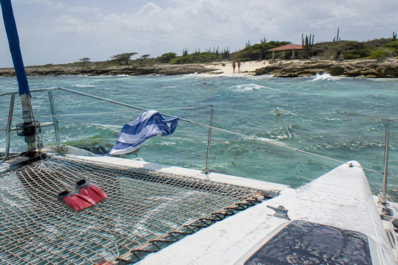 Catamaran anchored in clear shallow water beside a sandy beach
