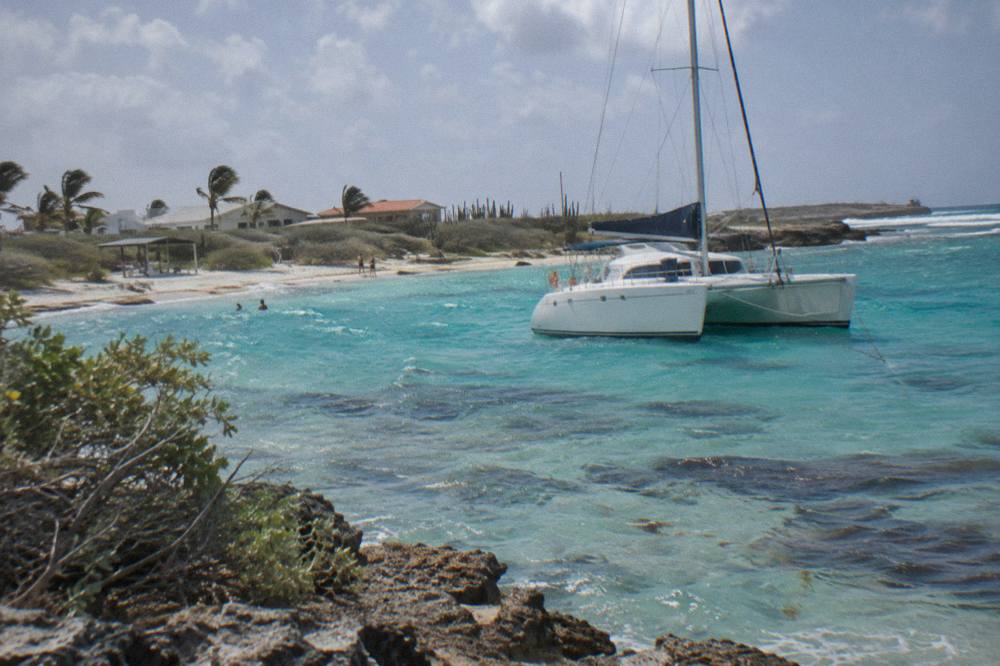 A catamaran anchored in clear shallow water near a coral reef