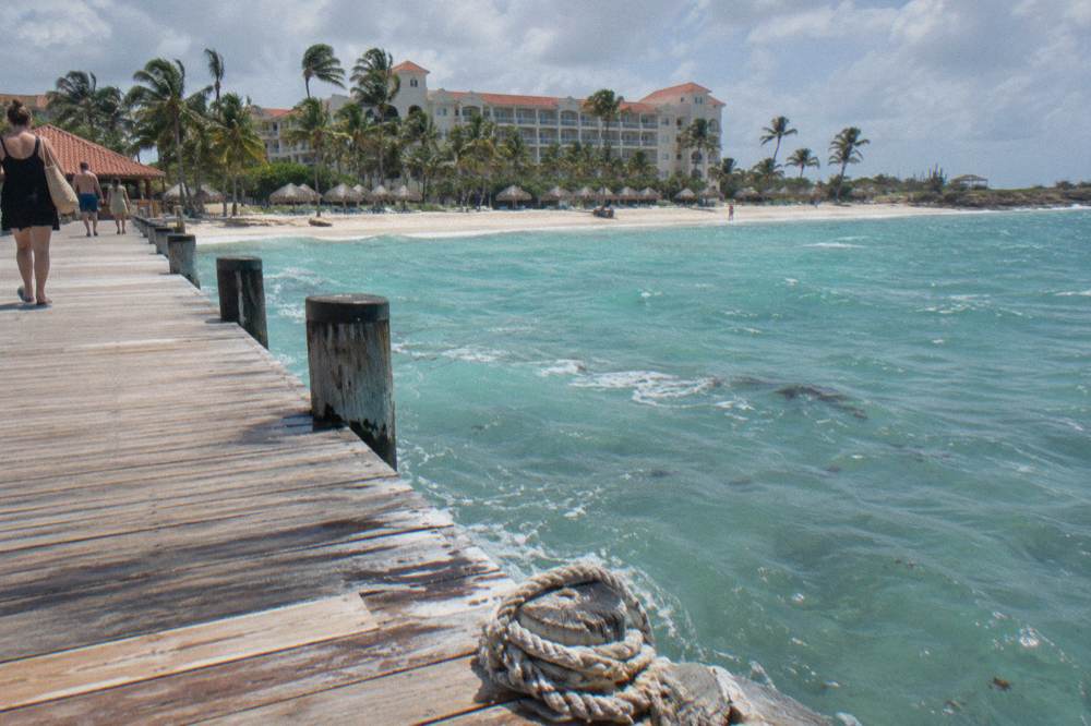 A wooden pier extending into calm blue water at a Caribbean beach