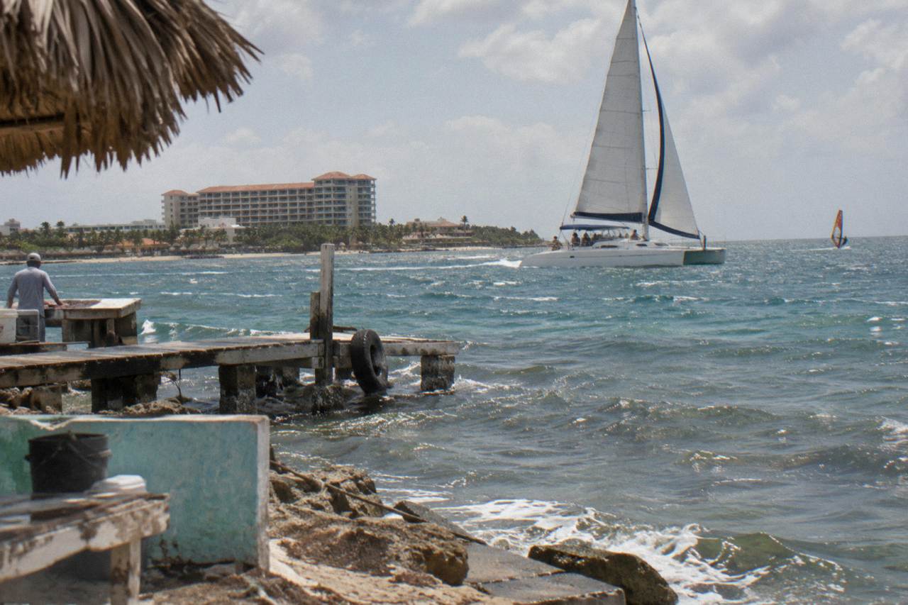 A catamaran sailing along a calm Caribbean coastline near sunset