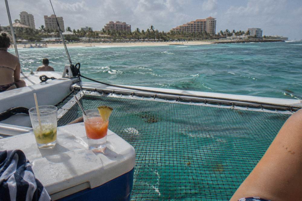 Cocktail glasses and a cooler on the shaded netting of a catamaran deck
