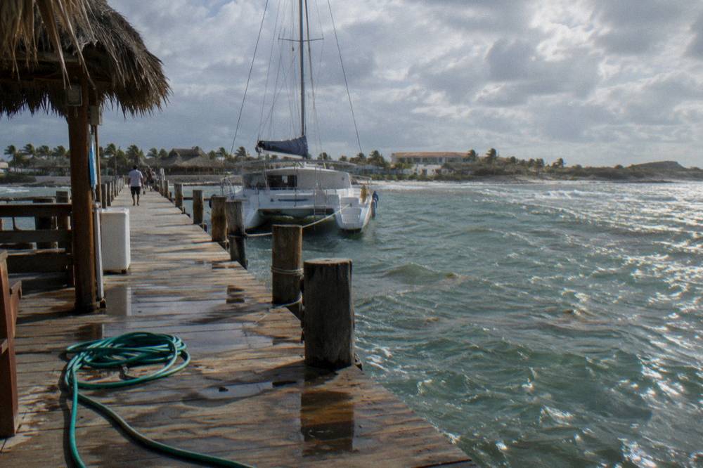 A moored catamaran at a wooden pier under a partly cloudy sky in the late afternoon