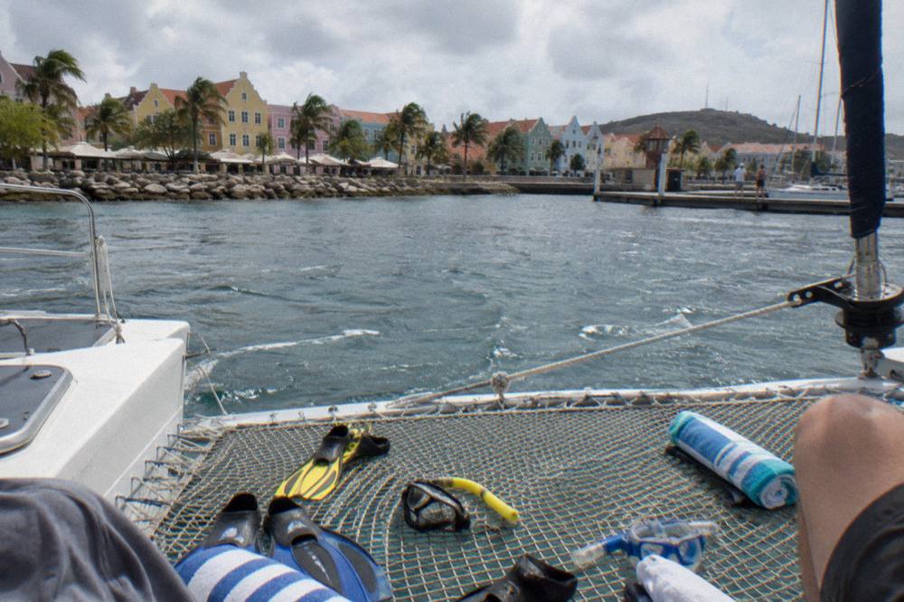 Snorkel gear and towels laid out on the netting of a catamaran deck