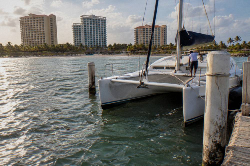 Catamaran moored at a Palm Beach pier in late afternoon light before a sunset departure