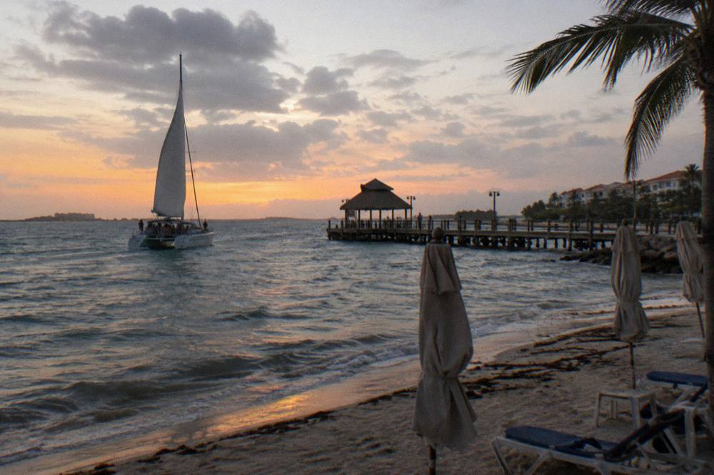 Golden evening light on the water as a catamaran returns to the Palm Beach pier after sunset
