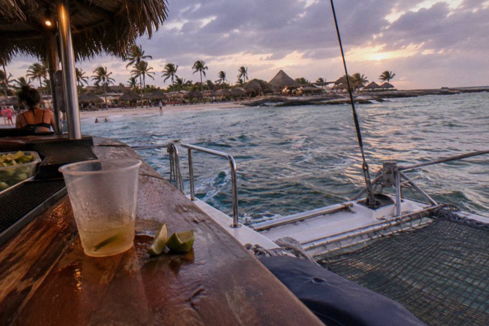 Open deck of a catamaran with drinks on the bar counter under an evening sky