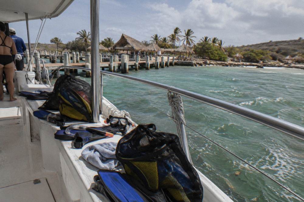 Open deck of a catamaran with snorkel gear laid out and turquoise water beyond