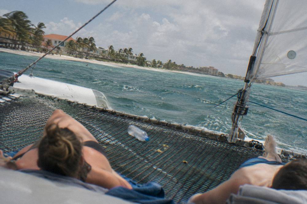 Passengers relaxing on the trampoline netting of a catamaran under sail