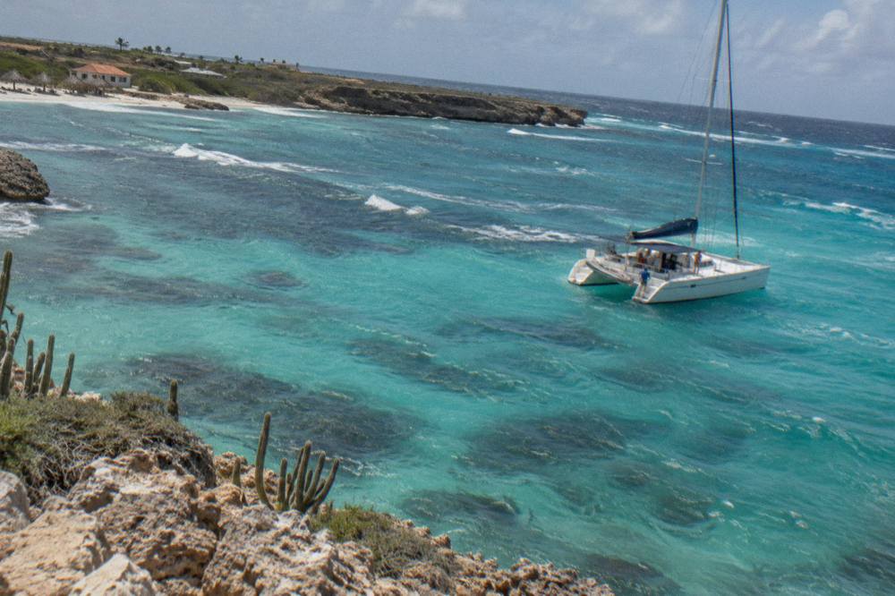 Calm turquoise water off the Aruba coast with a catamaran anchored near a reef
