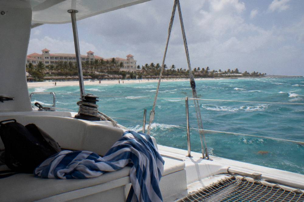 Catamaran deck in late afternoon light with calm sea and coastline in the distance