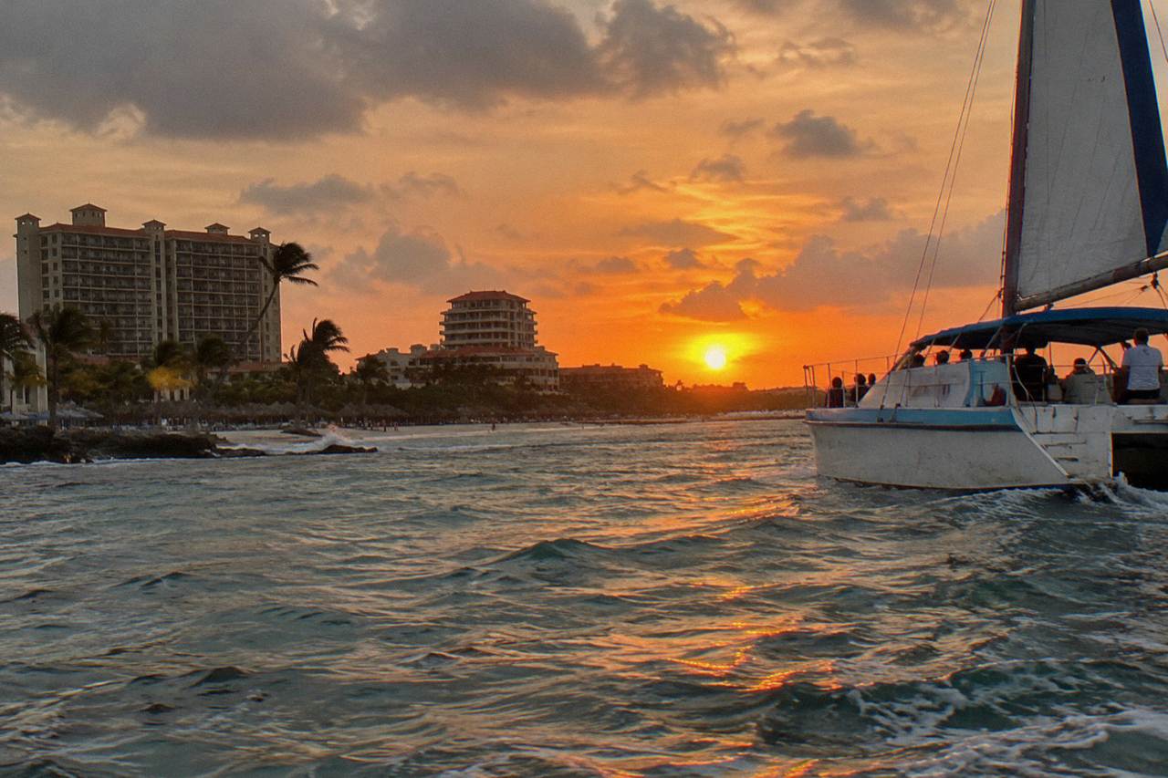 Catamaran sailing along the Aruba coastline at sunset with calm water