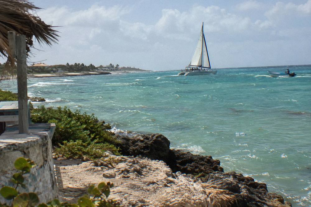 Catamaran under sail in calm water with another boat in the distance