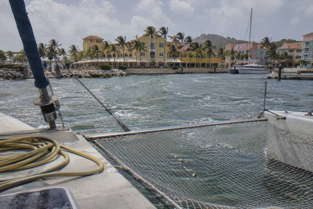 Wide catamaran deck with nets and rigging moored in calm blue water