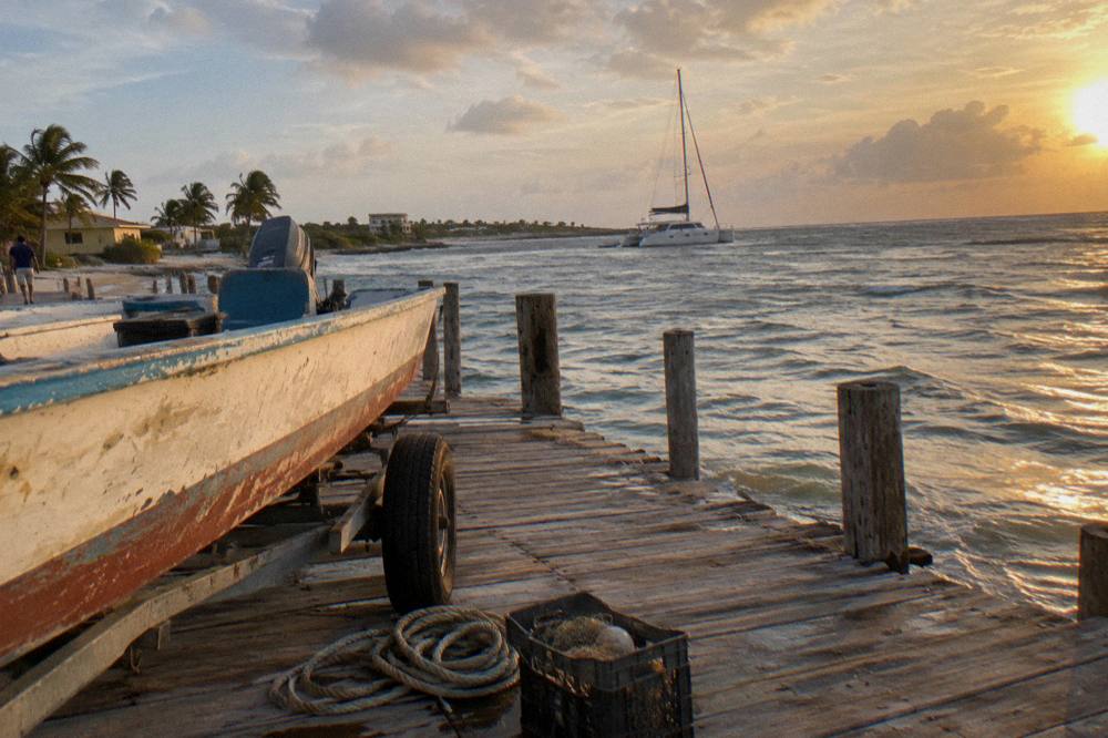 Catamaran anchored near a beach pier at golden hour with calm water