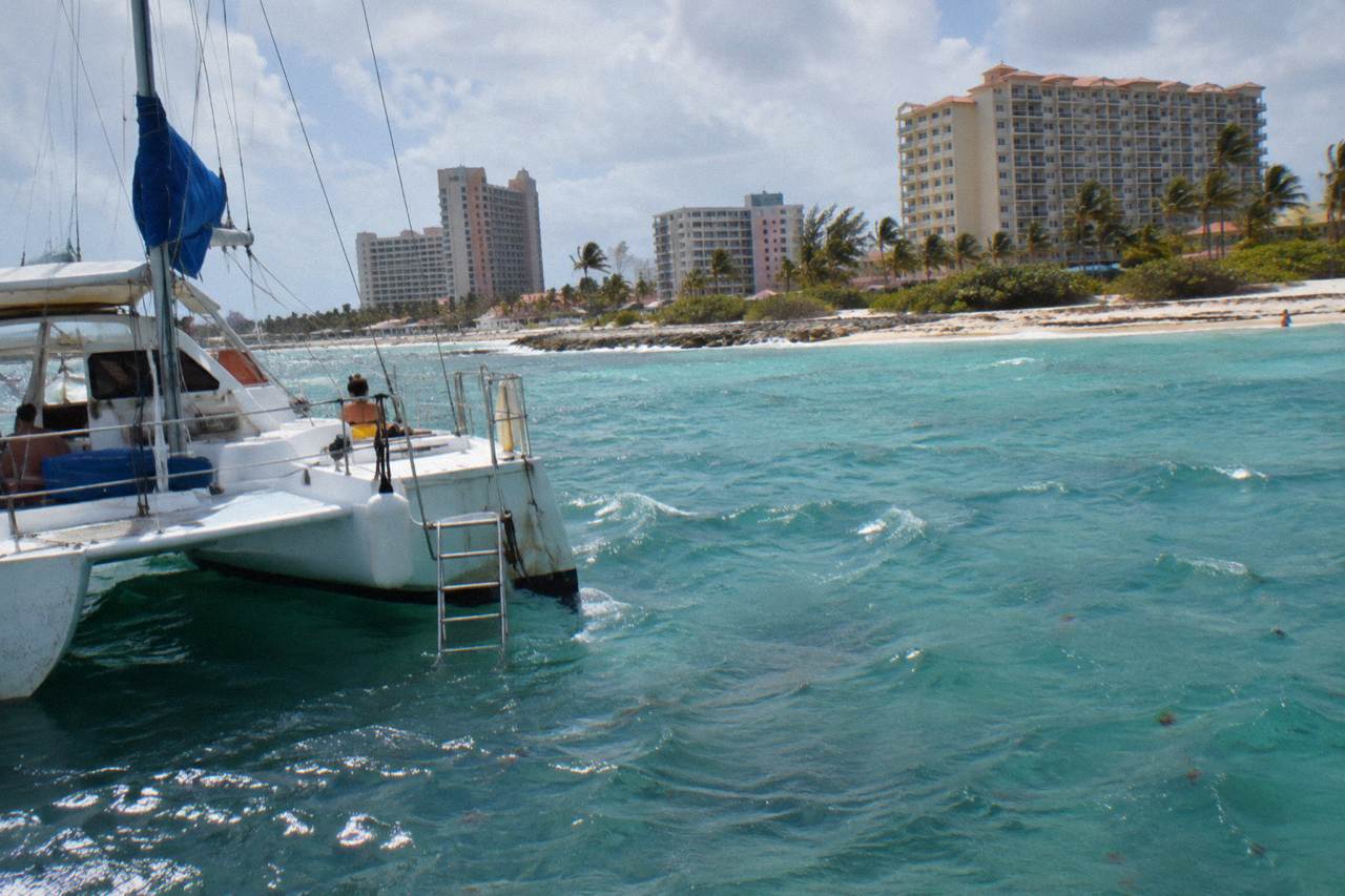 A white catamaran anchored in clear turquoise water near the Aruba coastline
