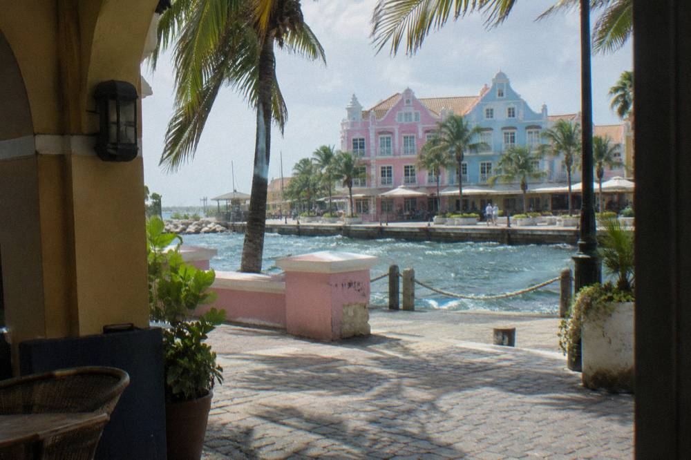 Pastel colored colonial style storefronts along a sunny waterfront street