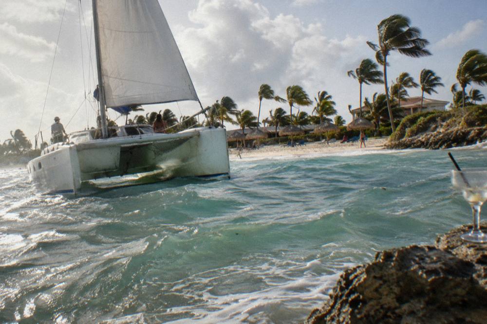 Catamaran under sail close to shore in golden late afternoon light