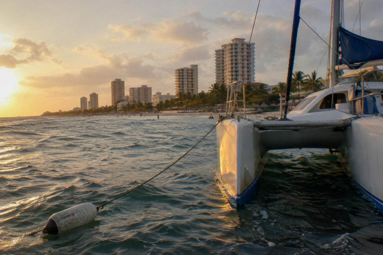 Catamaran anchored in calm turquoise water off the Aruba coast at golden hour