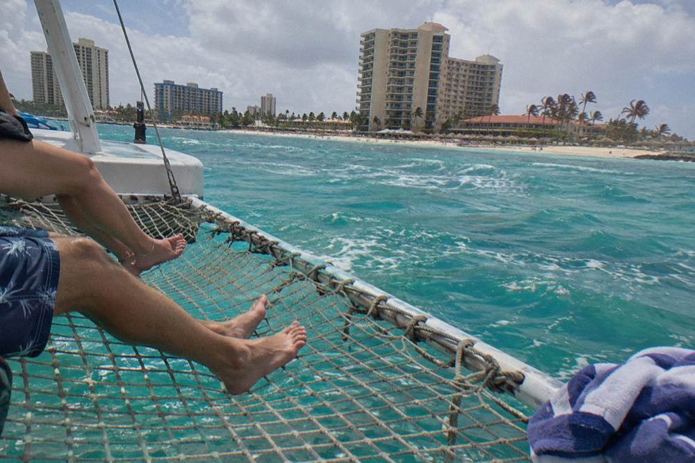 Passengers seated on a catamaran trampoline net over open water