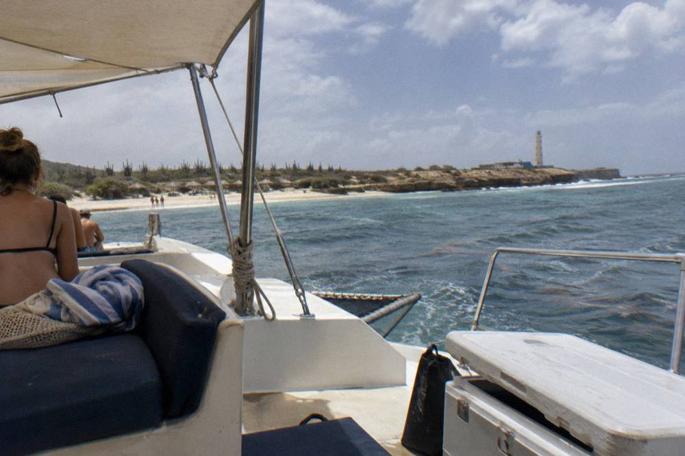 A catamaran deck set with seating and shade sail on calm water