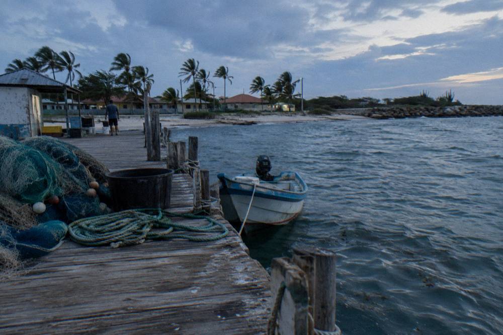 A quiet wooden pier extending over calm turquoise water at dusk