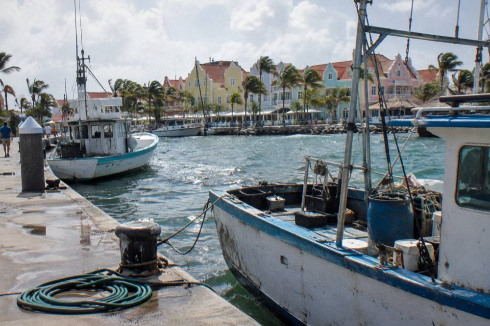 Oranjestad waterfront in Aruba with colorful buildings, moored boats and clear sky