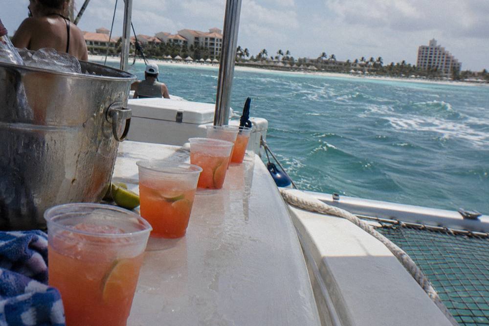 Open bar drinks lined up on a catamaran counter with crew serving guests