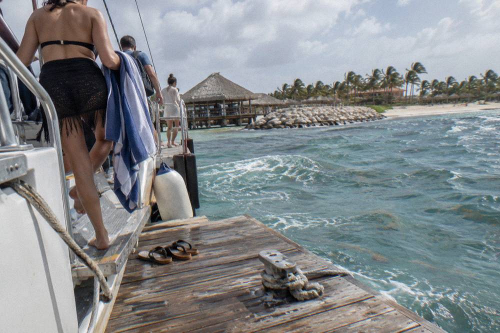 Guests stepping off a catamaran onto a wooden pier at the end of a sail