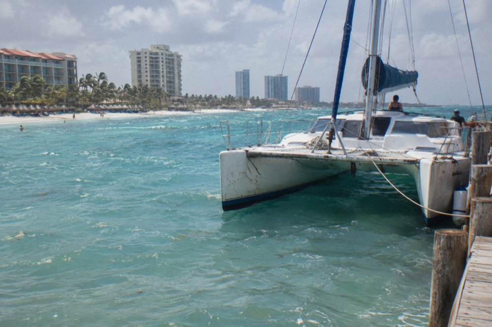 Catamaran moored at a Palm Beach pier with calm water and resort towers behind