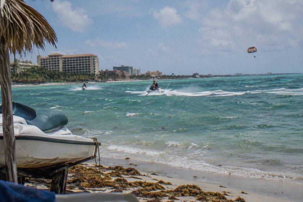 Turquoise water off Palm Beach with jet skis and a parasail canopy in the distance