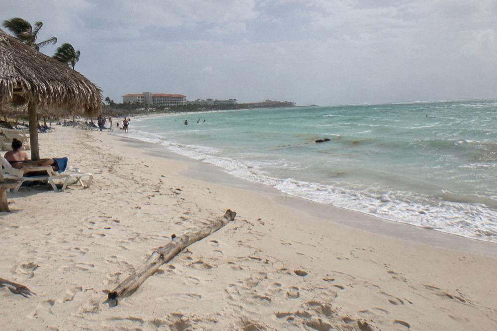 Wide sandy beach at Eagle Beach with shade huts and clear shallow water