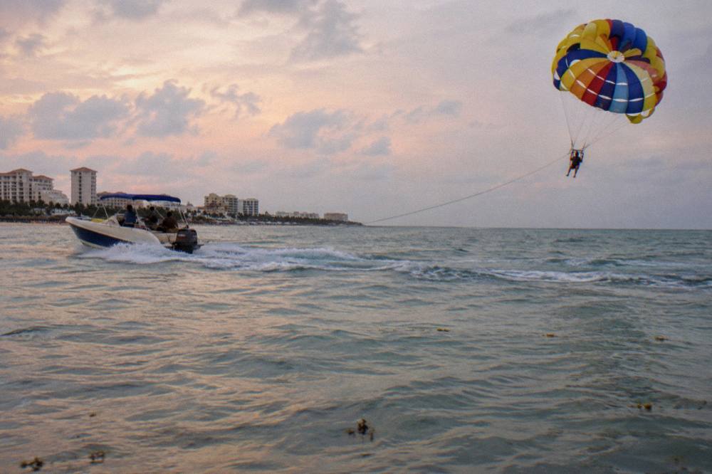 Speedboat towing a parasail canopy above calm early morning water