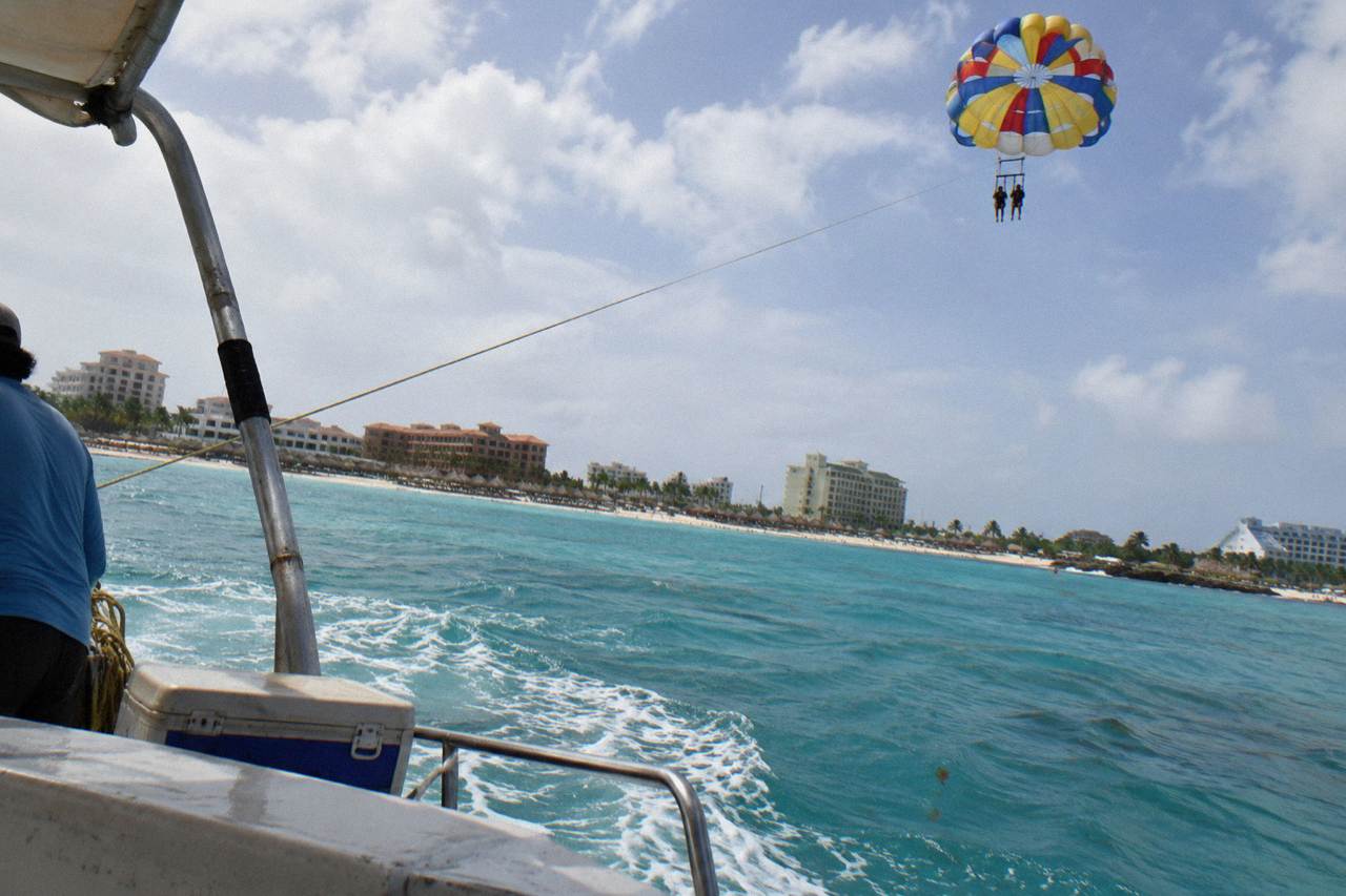 Parasail canopy high above the calm turquoise water off a palm-lined Aruba beach