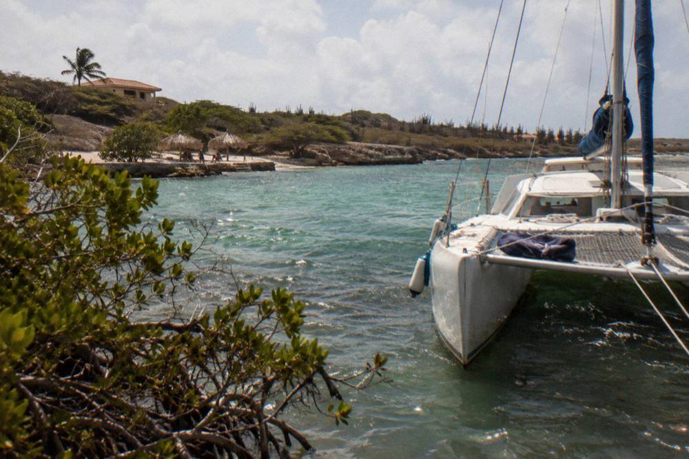 A folding chair and dry cover-up laid across the trampoline net of a catamaran in afternoon light