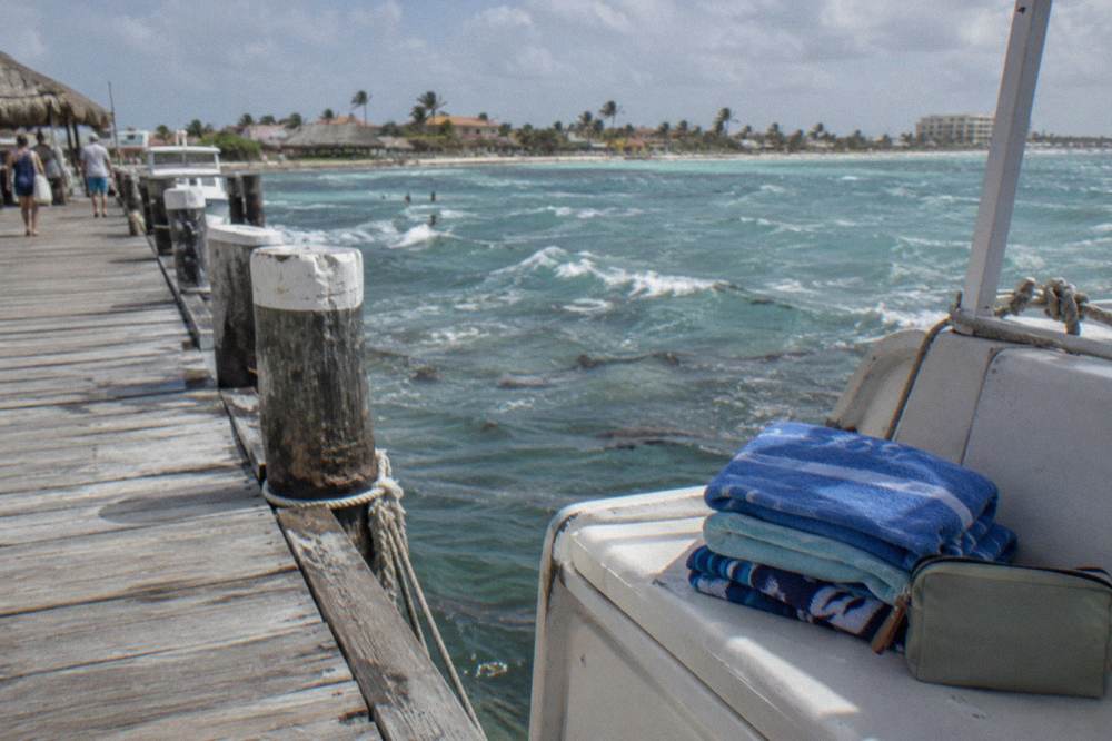 A stack of folded towels and a small pouch with currency resting on a boat bench