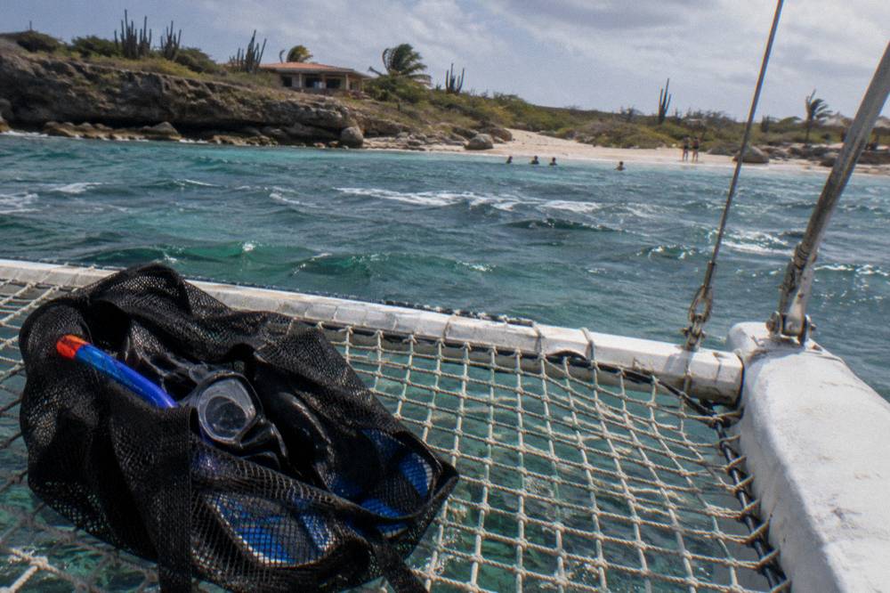 A mask, snorkel and fins clipped in a mesh bag on the trampoline net of a catamaran