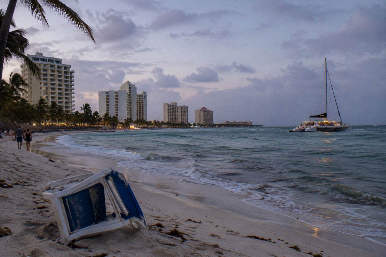 Dinner catamaran anchored off Palm Beach, Aruba, at early dusk with warm lamps lit